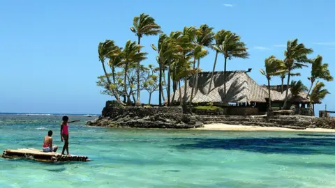 Getty Images Children float on a bamboo pontoon on the resort-studded Coral Coast of Fiji, 11 November 2003. 