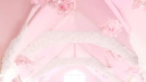 Glitterbels A pink church ceiling with hanging pink flowers and white cloud decoration cascading through