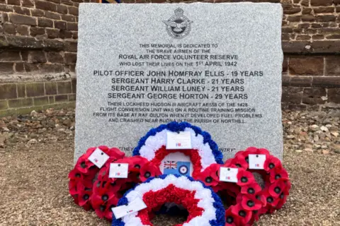 Sam Read/BBC A memorial stone commemorating Pilot Officer John Homfray Ellis, Sgt Harry Clarke, Sgt William Luney and Sgt George Horton. There are poppy wreaths laid at the base of the stone.