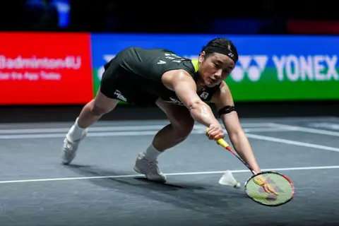 South Korea's An Se Young reaches out at full stretch with her racket for the shuttlecock as it nearly hits the ground at the front of the court at the All England Open Badminton Championships. 