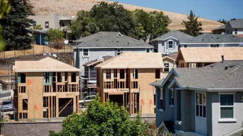 A row of houses under construction, some are more finished than others. 