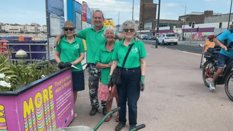 Wilderness to Wonderland Four people wearing green t-shirts smiling to camera on Margate seafront next to a raised flower bed they have planted 