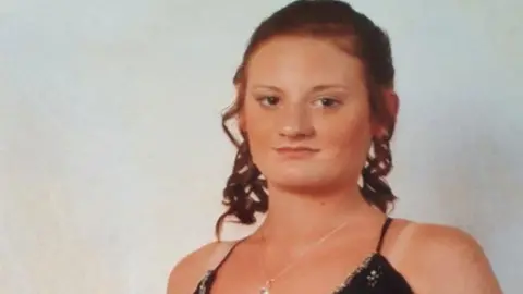 Family handout Head and shoulders image of Bethanie Clark in a black dress with thin straps and with her hair tied back and curled. She is suntanned and is smiling slightly. 