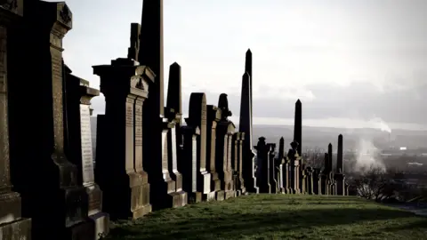 Jillian Neil Graves at the Necropolis, sloping downwards on a hill. The wider city can be seen in the background.