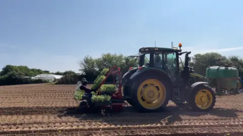BBC Farming tractor on Jersey field with people working on the back