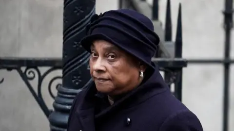 PA Media Baroness Doreen Lawrence wearing a purple coat and hat as she walks into court. 