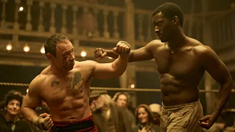 Disney Stephen Graham's character Sugar Goodson (left) wears red boxing shorts and has a cut on his right eye as he fights boxer Hezekiah Moscow, played by   Malachi Kirby (right)