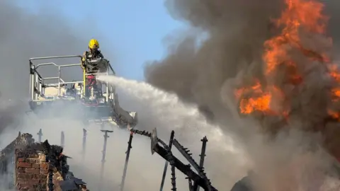 A firefighter on a crane shooting water jets down towards a building