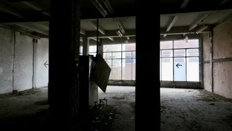 Clare Worden/BBC Interior image of a derelict building. It is bare and dark. Large windows overlook buildings on the other side of the street.