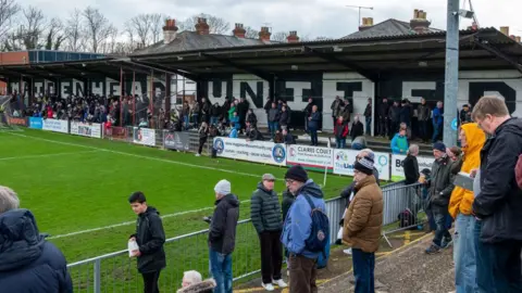 Football fans watch a National League match against Chesterfield at Maidenhead United's York Road ground on 1 April 2023 in Maidenhead.