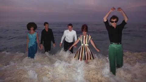 Getty Images The B-52s wade through the surf against a sunset skyline in 1982