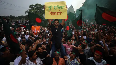 Getty Images Bangladeshis wave the national flag 5 August, 2025 as they celebrate one year since Sheikh Hasina was ousted from power