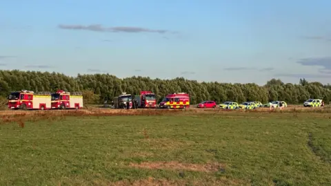 The same scene from further out, with police cars also visible.