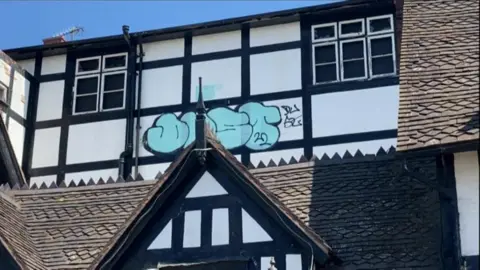 Graffiti and broken windows on a black and white timber-framed building