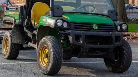 Getty Images A green John Deere XUV 855D S4 crossover utility vehicle is parked in front of a building. - stock photo