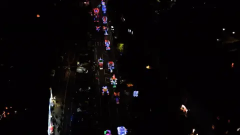 Corbett Services A drone shot showing illuminated tractors on a road on an otherwise dark view