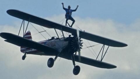 Elderly woman strapped to the upper wing of a biplane in midair