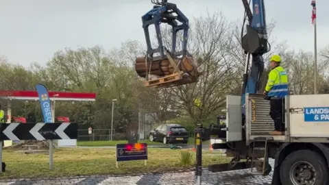 St Swithuns Lodge Image of a crane putting an English oak monk statue into position on a roundabout in Abingdon.