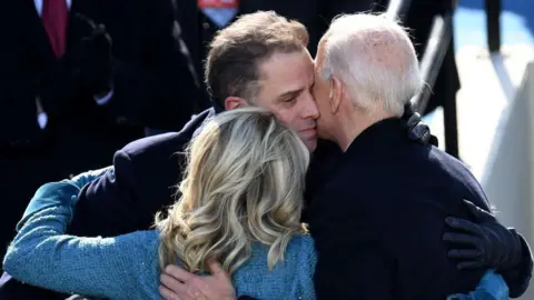 US President Joe Biden (R) hugs his son Hunter Biden (C) and US First Lady Jill Biden
