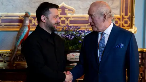 PA Media President Zelensky smiles as he shakes hands with the King at Buckingham Palace.