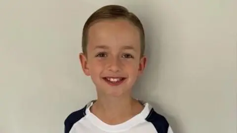 Dennis family George Dennis smiling while wearing a white Tottenham Hotspur top.