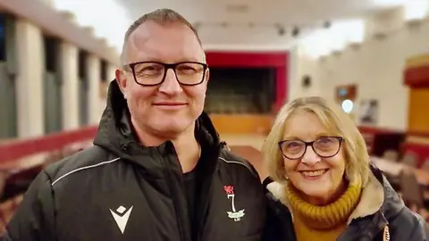 Dafydd Francis and his mother standing facing the camera in Onllwyn miners welfare hall.