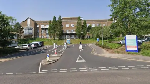 Entrance to hospital with a brown-bricked building in the background.