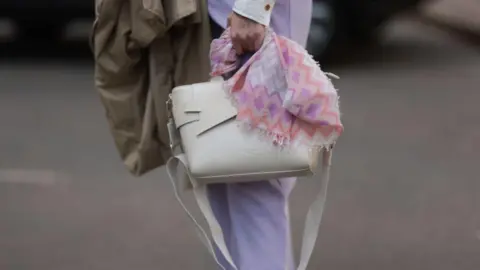 Getty Images Influencer carrying a white Ted Baker handbag and a pink patterned scarf