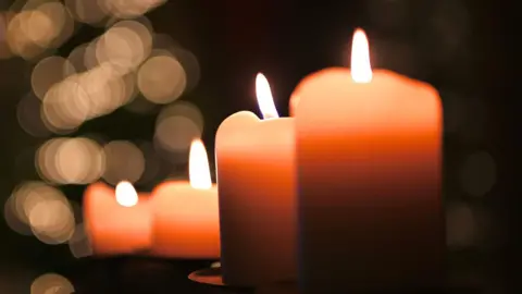 A number of candles lit up with a dark background. 