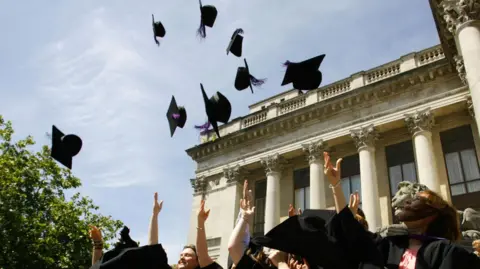 PA Media New graduates throw their mortarboard hats into the air following their graduation ceremony at Portsmouth's Guildhall