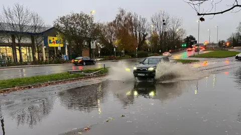 A car driving through a large puddle outside a Lidl store