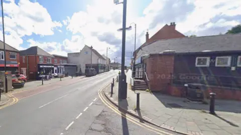 This generic street image shows Cannock Road going from the bottom left to the centre of the photo. Buildings are on both sides of the street and the image is taken at a junction, with part of another road being visible at the bottom of the photo in the middle.