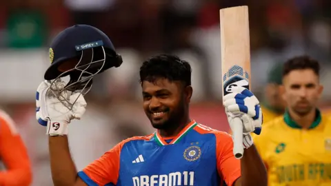 India opener Sanju Samson raises his bat to celebrate scoring a century against South Africa