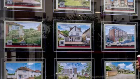 Getty Images Man walks past a display of properties in an estate agent's window in Walton-on-Thames