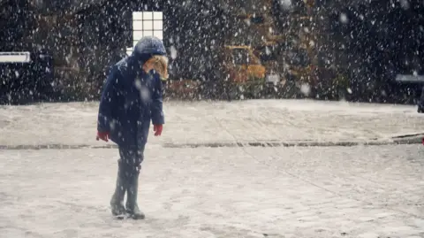 A child stands in a snowy road
