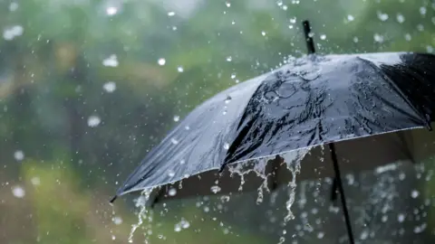 A black umbrella with heavy rain pouring down onto it. 