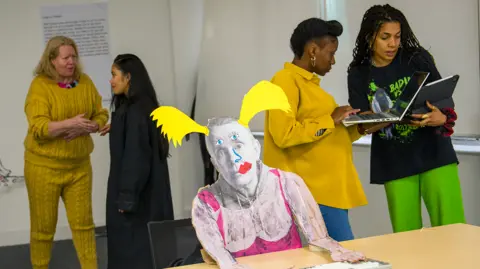 BBC Actors and the director rehearse and discuss All The Rage in the repurposed office space with a life-sized cardboard cut-out of writer and artist Lucy Edkins with added colourful pigtails, lipstick and dress in the centre of the photo