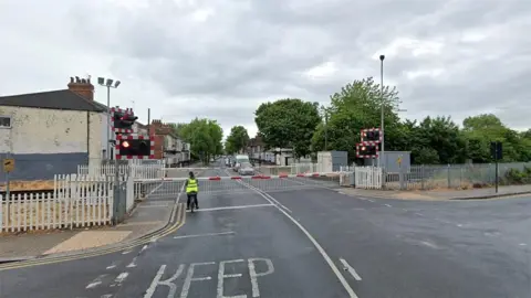 Google Google street view of the level crossing on St George's Road in Hull. The barriers are down and the warning lights are flashing as a lone cyclist wearing a high visibility jacket waits at the gates 