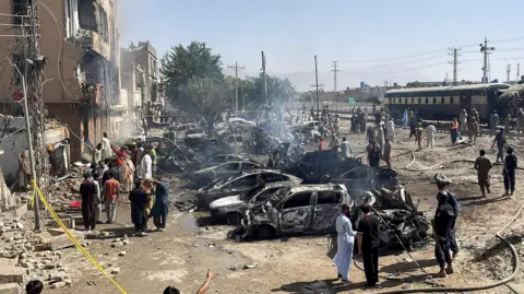 People and police officers gather after a blast near a railway track in Quetta, Pakistan