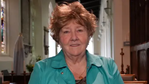 Qays Najm/BBC Lady in a pale green jacket with the altar of a church in the background