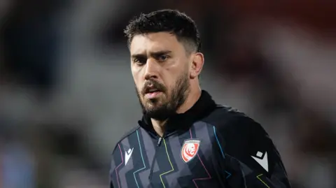 Gloucester rugby lock Matias Alemanno looks on during the warm-up for a Premiership Rugby game, wearing a black quarter-zip training top