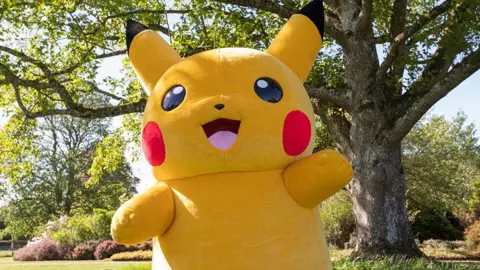 National Trust Images/James Dobson Pokemon character Pikachu standing by a huge in a garden owned by the National Trust on a sunny day. 