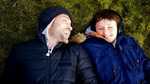 Richard and Jaco, taken when Jaco was 11, lying on grass and laughing 