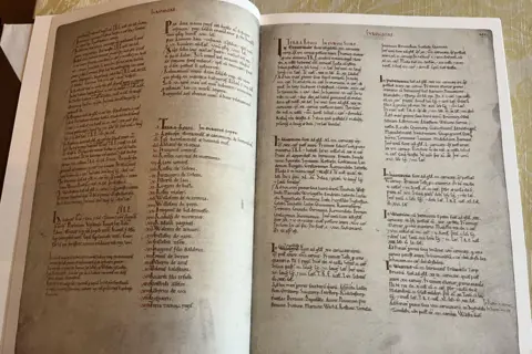 A photograph of a copy of the Domesday Book - open to pages with cursive text in columns. 