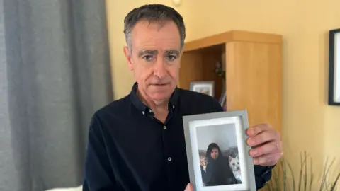 Pete holding an image of his daughter Hannah