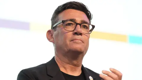 PA Media Andy Burnham. He has dark hair, wearing glasses, a black blazer and black t-shirt.