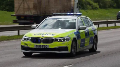 A police car travelling on a main road.