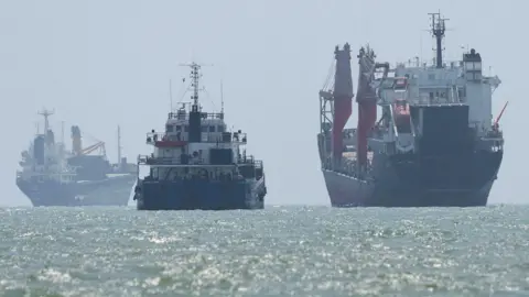 Vessels in the Strait of Hormuz are visible near the beach of Bandar Abbas, Iran, August 25, 2026