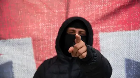 Harvey Tomlinson A masked protester in front of a Union Jack in Nottingham