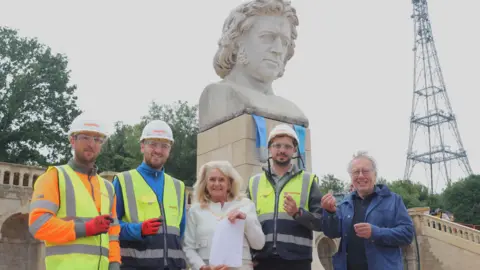 Crystal Palace Park Trust Marius Craciun Dorin, Josh Smalls, Maylim, councillor Christine Harris, Mayor of Bromley, Florin Chiric, Maylim, Martin Tempia, co-chair at Crystal palace Park Trust. Harris is in the middle holding up the note, while the rest of the people pictured are holding up one of the coins the note came with.